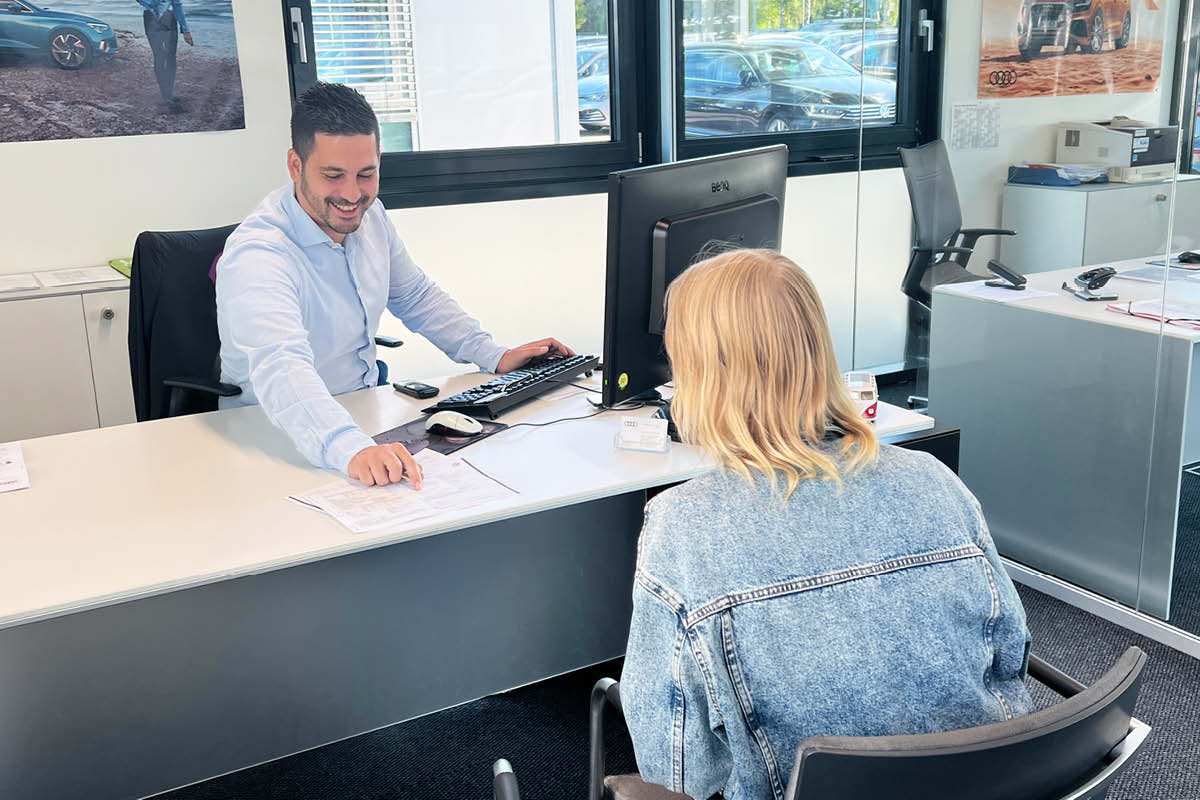 Mitarbeiter berät Kundin im Autohaus